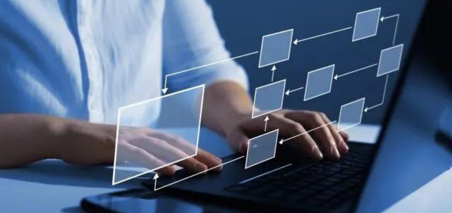Persoon die typt op een laptop met een smartphone naast zich, met een workflowdiagram dat stappen van een geautomatiseerd printproces weergeeft. 