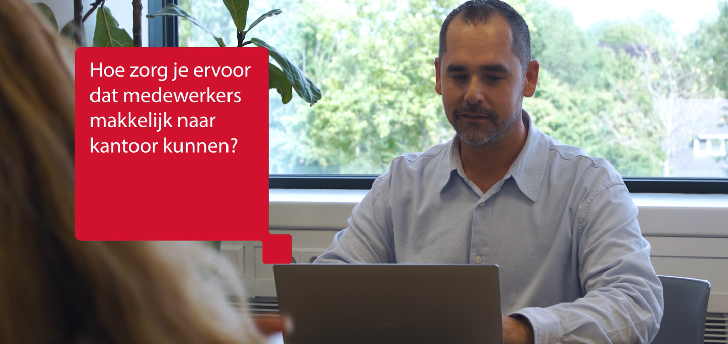 collega kijkt naar scherm, rood tekstveld Hoe zorg je dat medewerkers makkelijk naar kantoor komen?