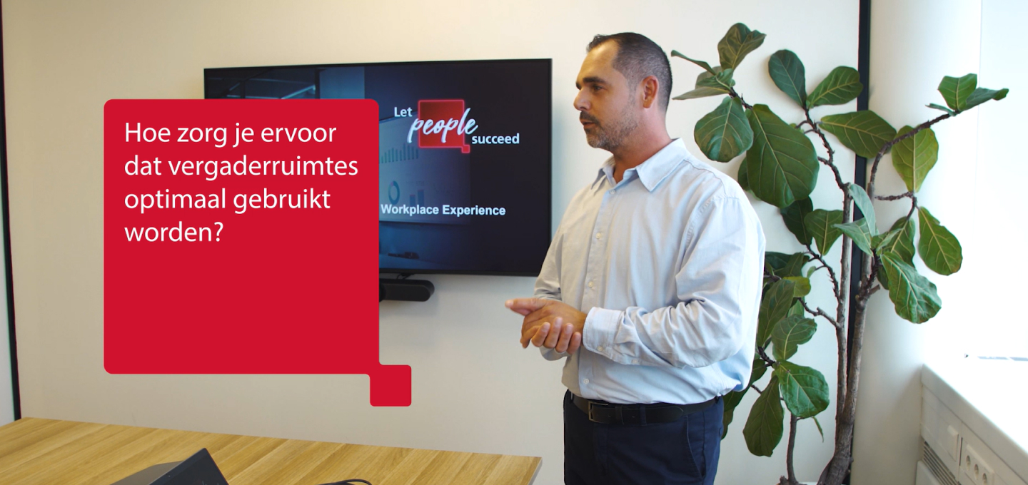 collega presenteert in vergaderruimt - rood tekstvelt met: Hoe zorg je ervoor dat vergaderruimtes optimaal gebruikt worden?\